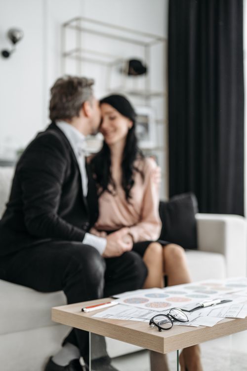 Free A loving couple sharing a tender moment indoors, sitting on a sofa in a modern setting. Stock Photo