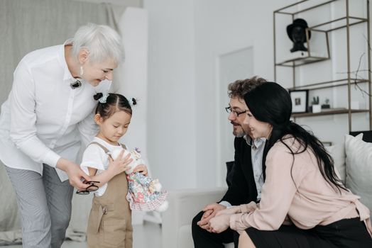Happy family scene with adoptive parents and child holding a plush toy, creating joyful memories.