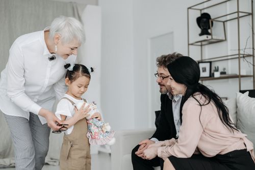Free Happy family scene with adoptive parents and child holding a plush toy, creating joyful memories. Stock Photo