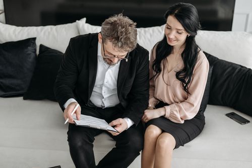 Free Business couple reviewing documents together on a couch, highlighting teamwork and success indoors. Stock Photo