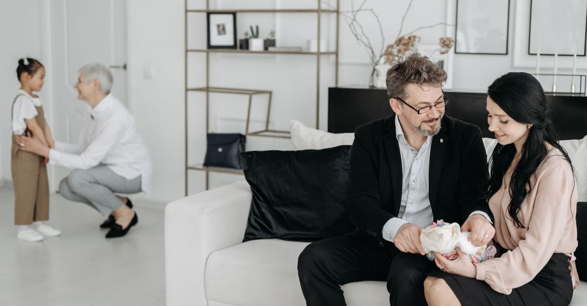 Couple with social worker and child, embracing new family moments in a cozy living room.