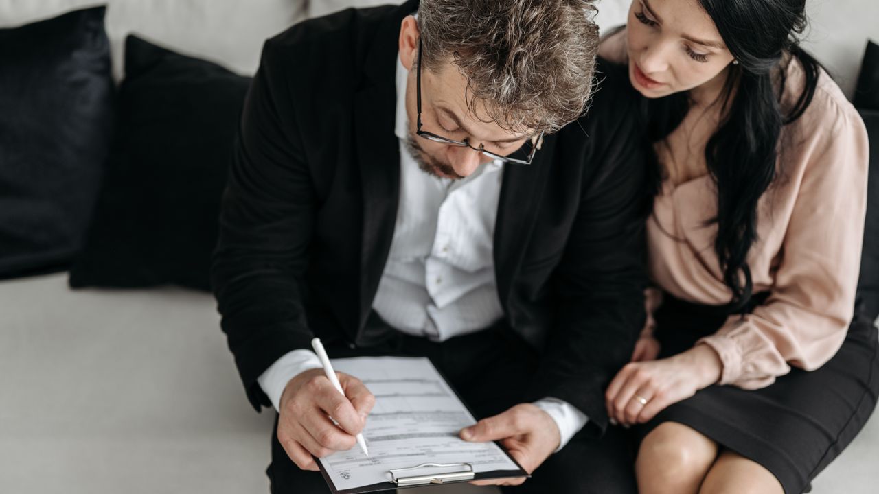 An adult couple sitting together reviewing documents in a modern indoor setting.
