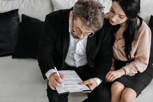 An adult couple sitting together reviewing documents in a modern indoor setting.