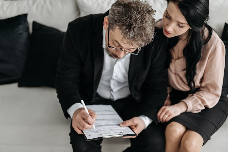 Woman Sitting Beside A Man Filling Out A Form