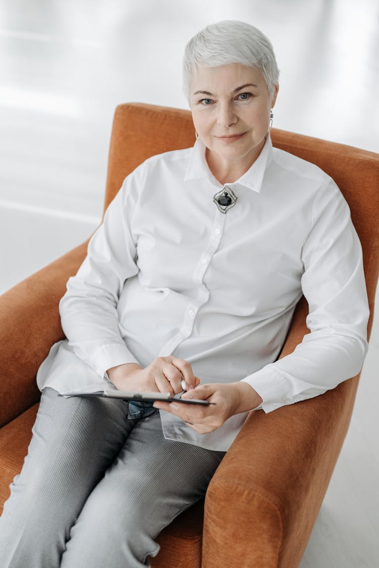 A Woman In White Long Sleeves Sitting On Brown Chair