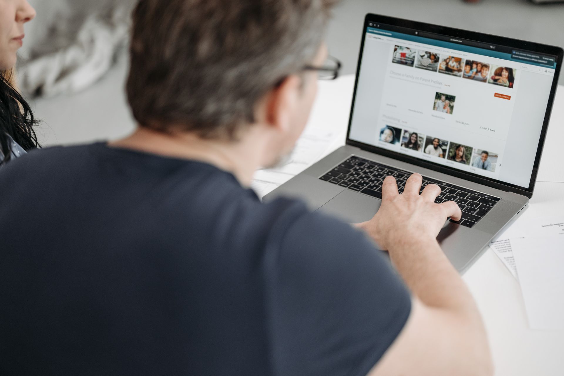 Adult male viewing online profiles on a laptop, engaged in digital browsing indoors.