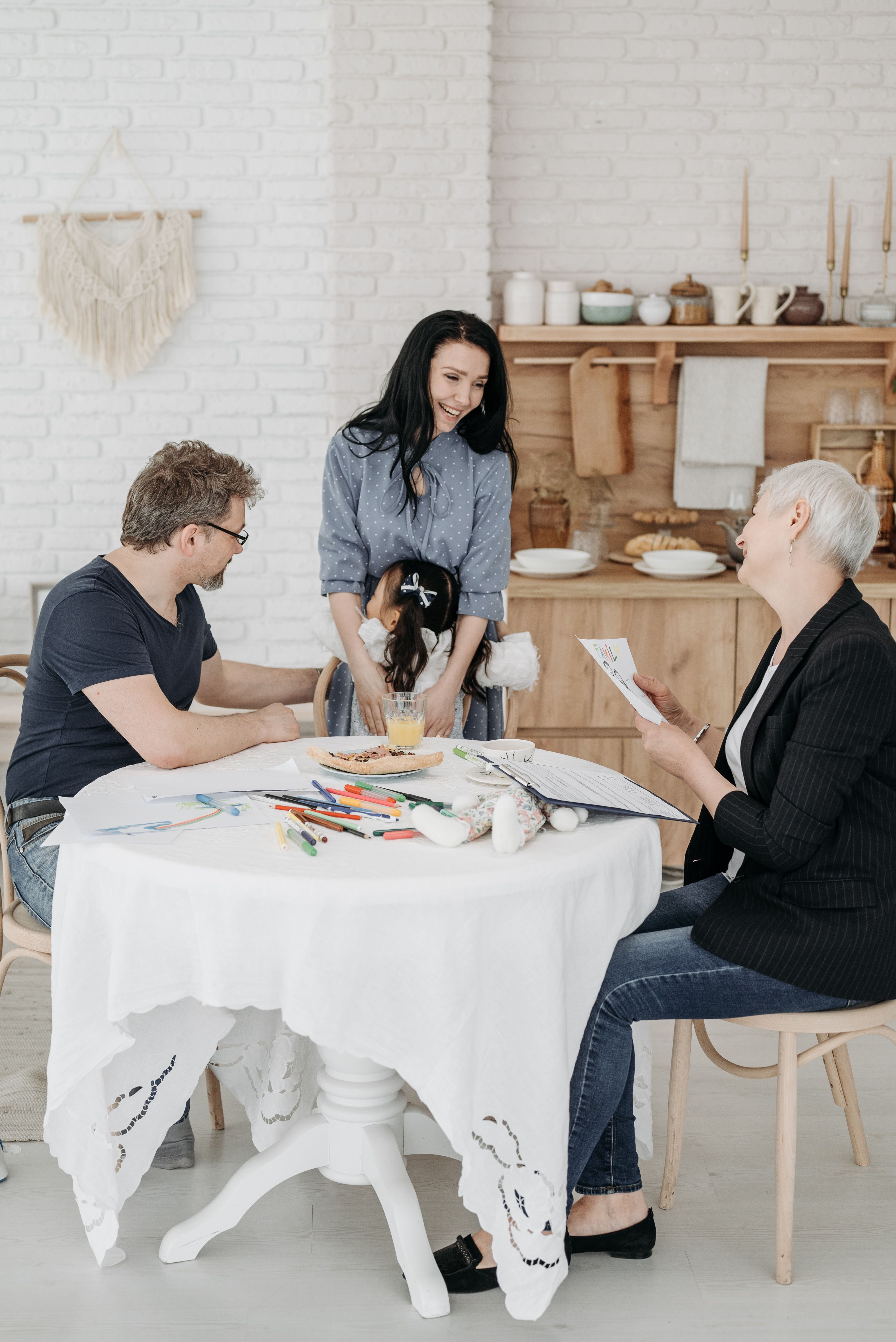 A warm family moment indoors with parents and child engaged in arts and crafts activities.