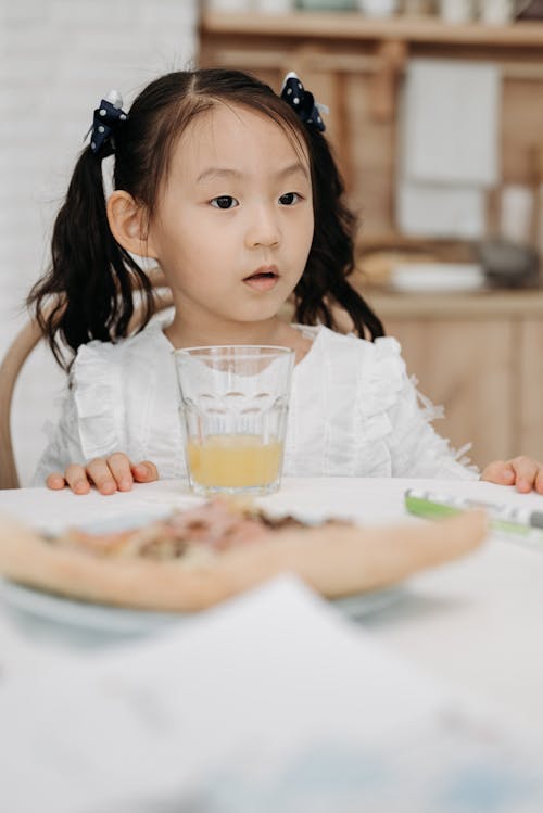 Photograph of a Girl Near a Glass of Juice