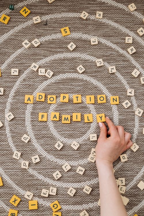 Free Top view of scrabble tiles forming 'Adoption Family' on textured carpet. Stock Photo