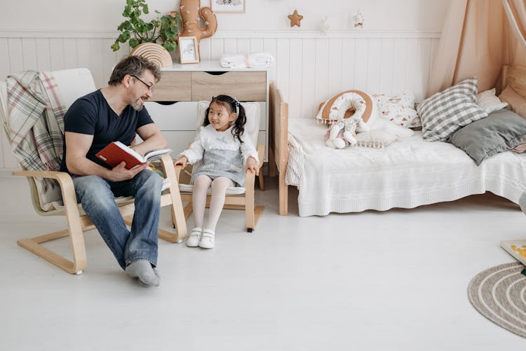 Man Reading A Book To His Little Daughter