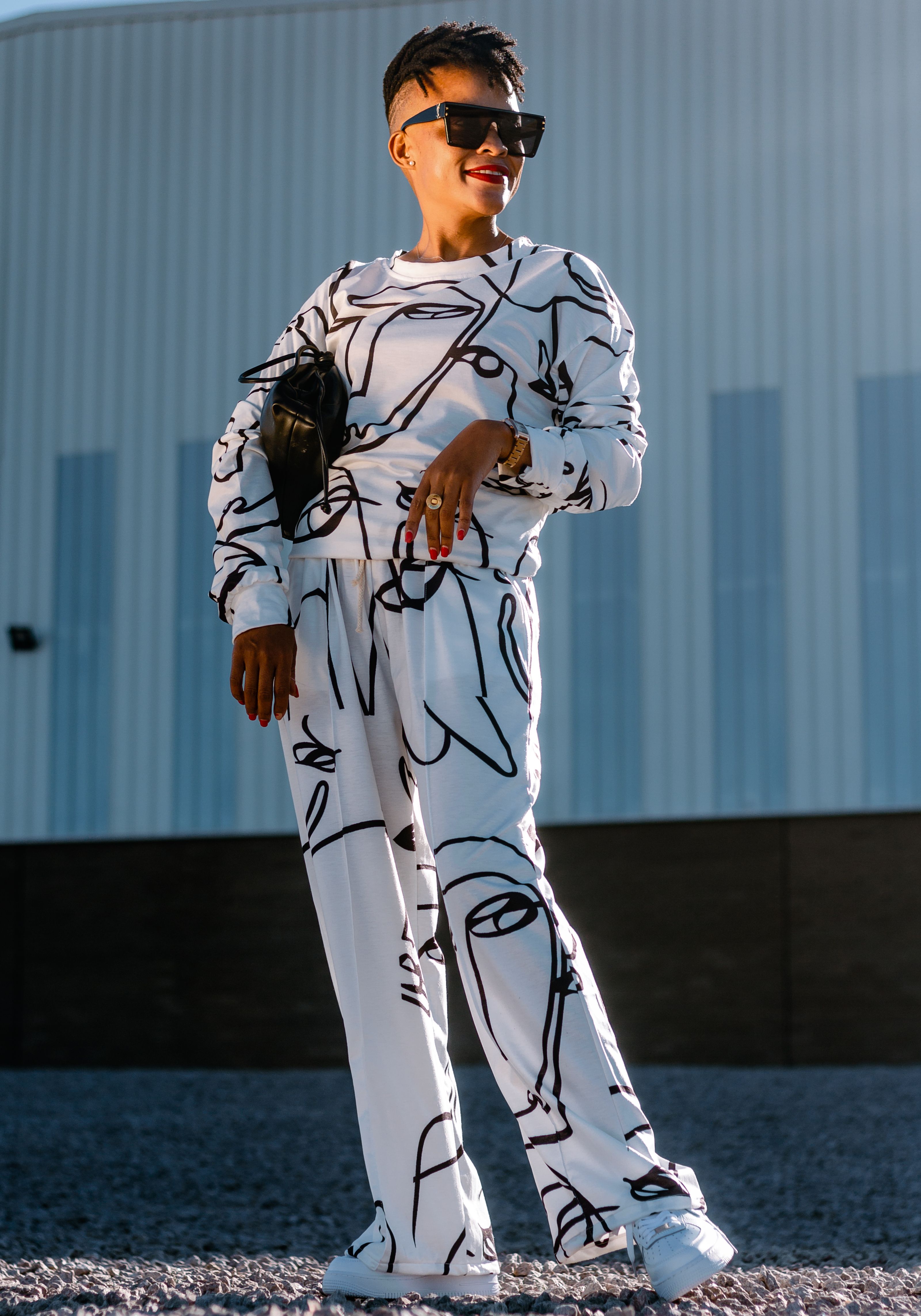 Mulher fashion posando em um conjunto preto e branco combinando contra um prédio contemporâneo.