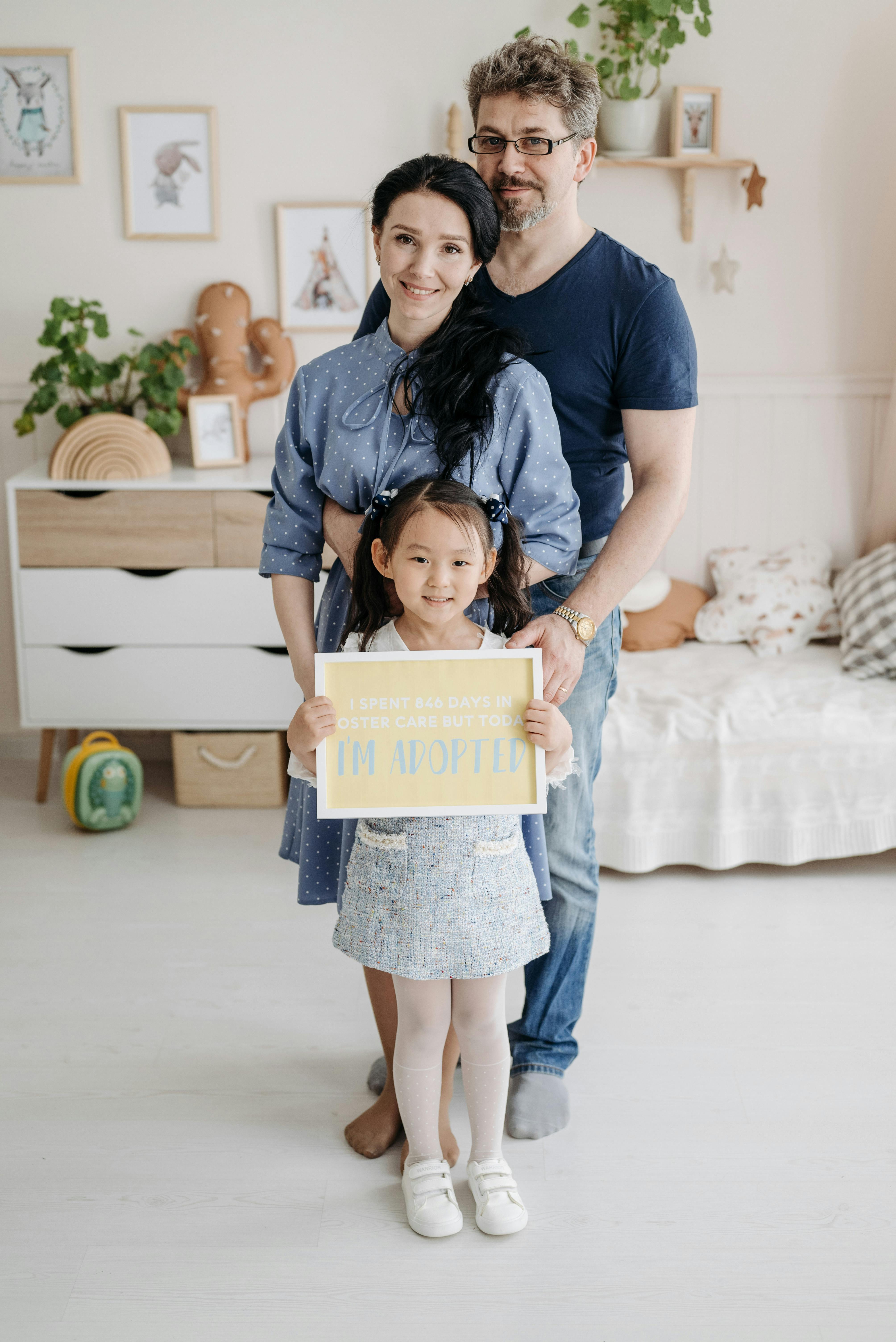 A joyful family portrait with adoptive parents and child in a cozy home environment.