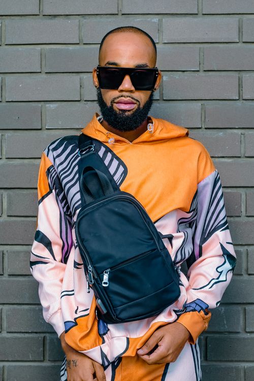 Free Hip fashion model poses confidently in urban setting wearing bold colors and sunglasses. Stock Photo