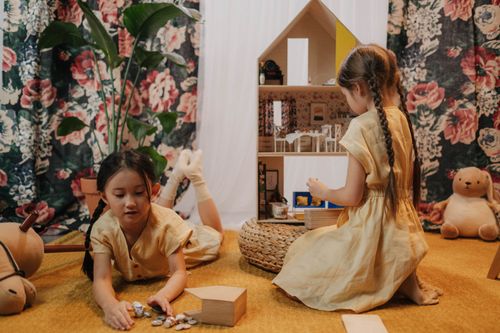 Free Two young girls playing with a dollhouse in a cozy, colorful indoor setting, embodying playful childhood moments. Stock Photo