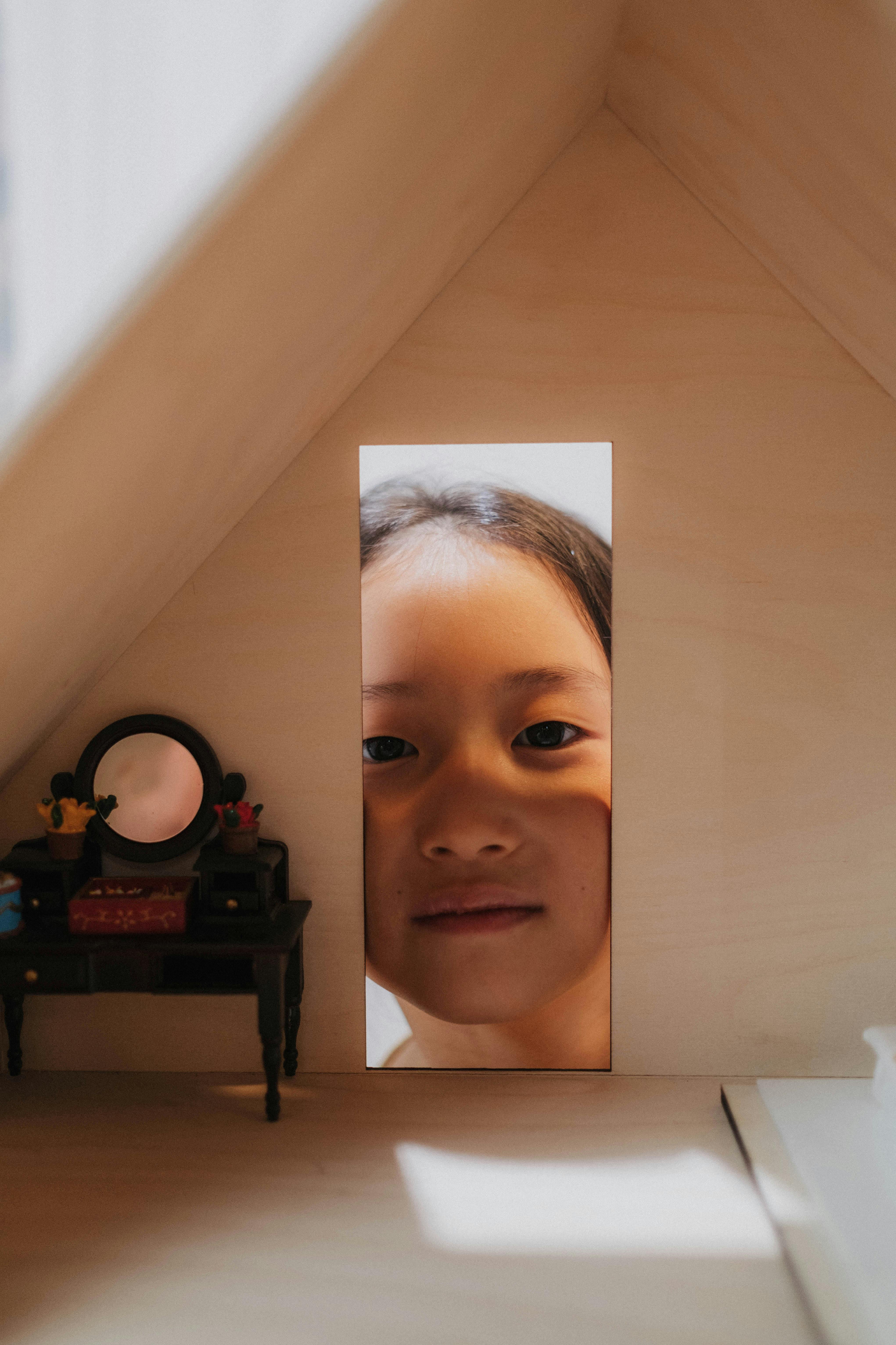 girl peeking through a doll house