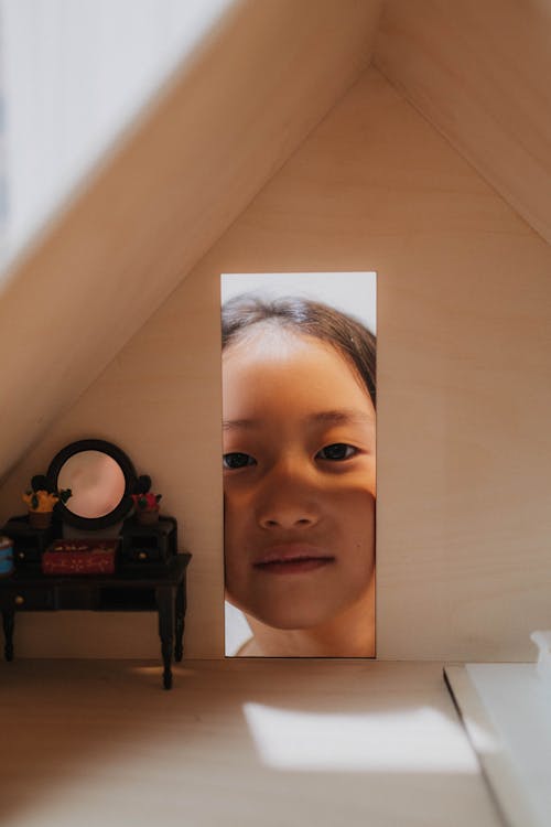 Free Girl Peeking Through a Doll House Stock Photo
