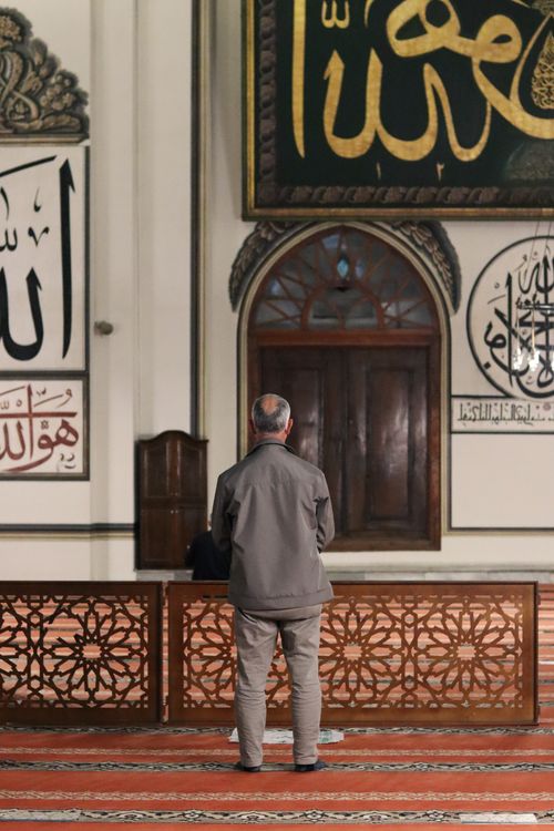 Free Back view full body of unrecognizable Muslim male in casual clothes standing in mosque with arched doorway Stock Photo