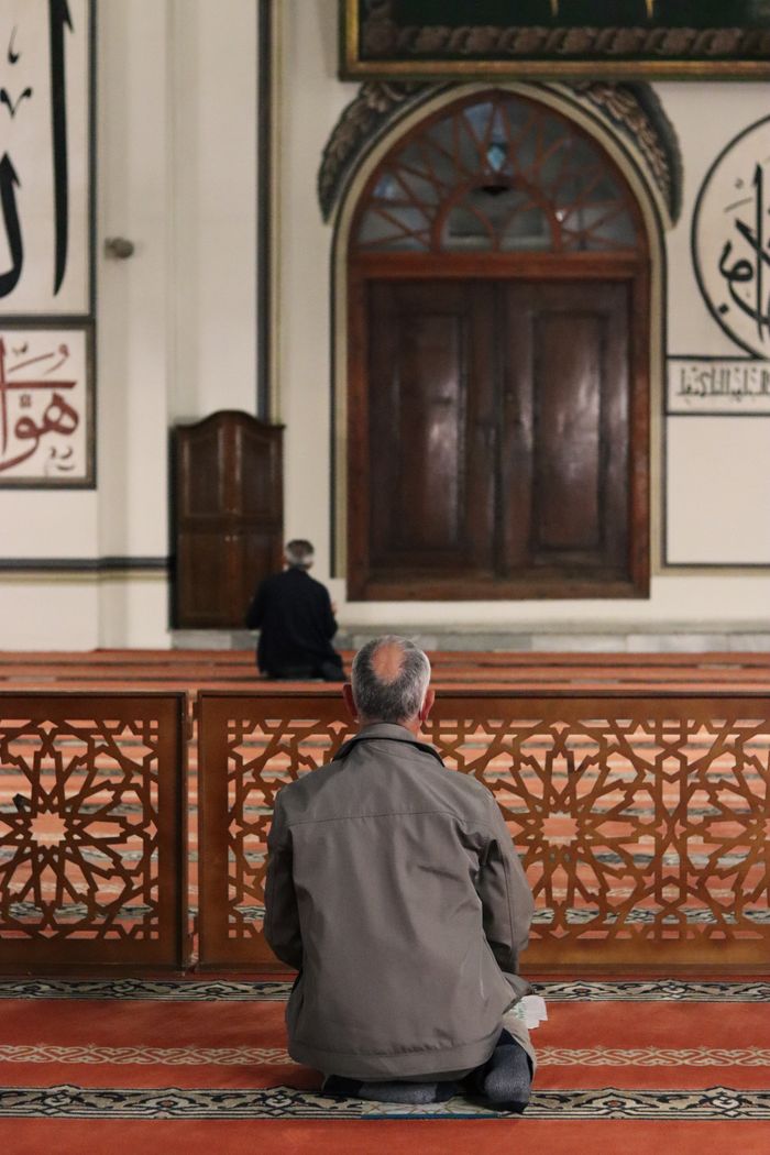 A worshipper kneeling in prayer near the front of a mosque