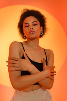 Stylish portrait of a woman posing with a warm orange background, evoking confidence and elegance.