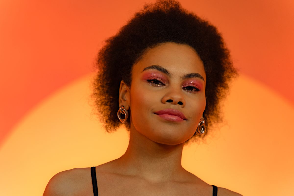 Studio portrait of a smiling young woman on a warm gradient backdrop — AI25.Studio Studio on Pexels