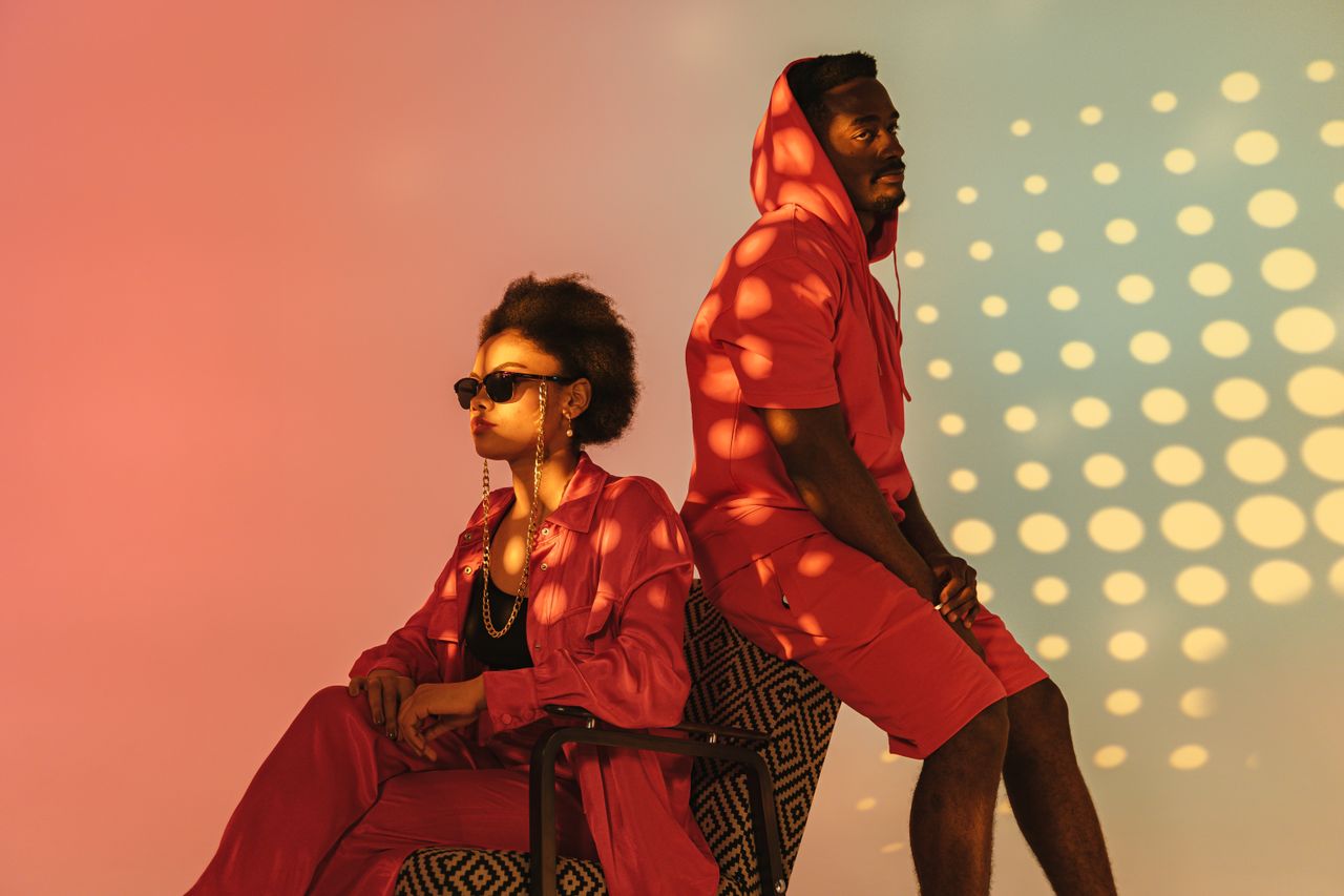 two people in fashionable red attire posing against a dotted backdrop