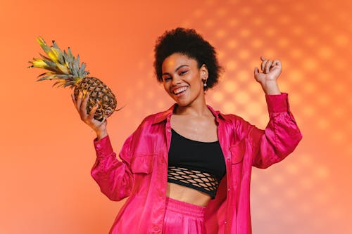 Woman in Pink Jacket Holding Pineapple