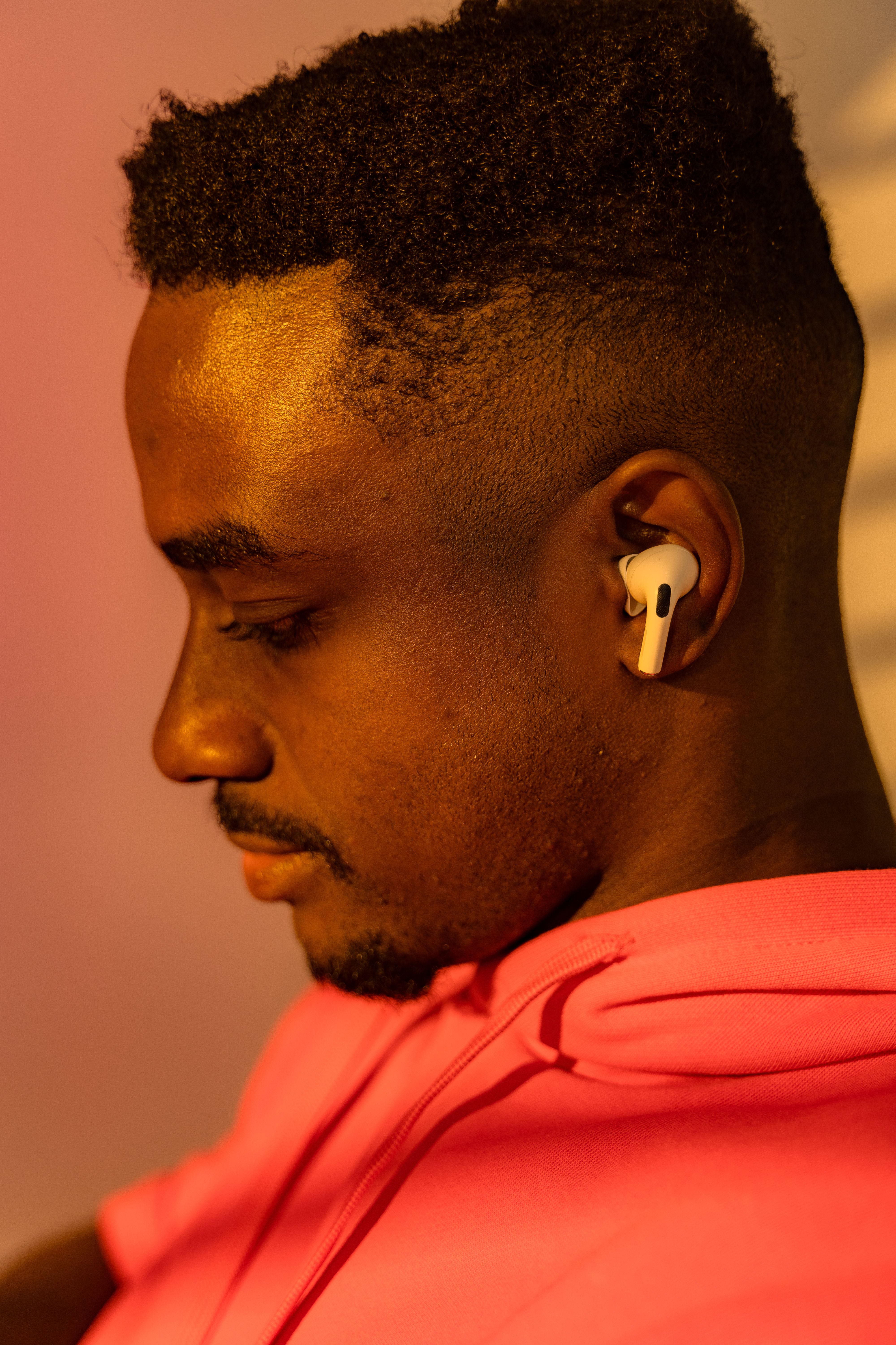 Close-up of a man wearing earphones, seen from the side in warm light, conveying serenity.