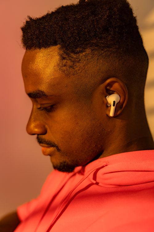 Free Close-up of a man wearing earphones, seen from the side in warm light, conveying serenity. Stock Photo