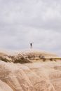 Man in Black Shirt Standing on Brown Rock Formation Under White Clouds