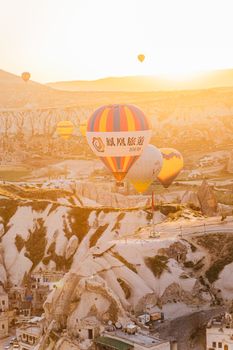 Scenic view of hot air balloons floating over Cappadocia's unique landscape during sunrise.