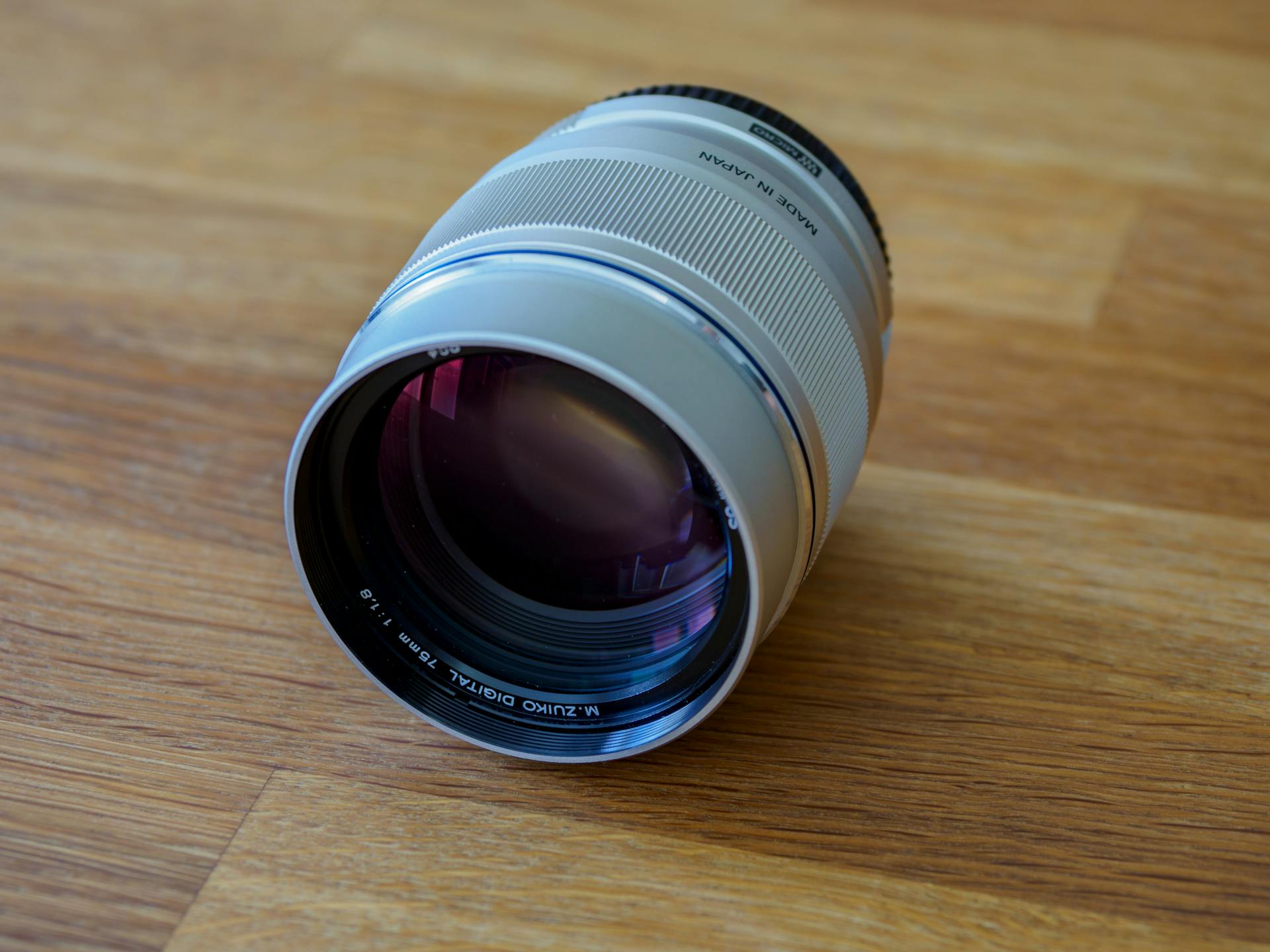 Detailed close-up of a prime lens resting on a wood surface, showcasing optical quality.