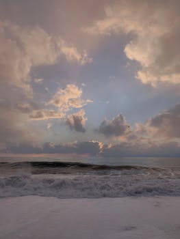 Captivating ocean waves under a dramatic sunset sky, featuring pink and blue clouds.