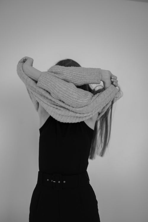 Free Artistic black and white photo of a woman taking off a sweater, indoors. Stock Photo