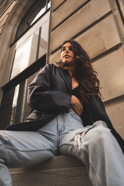 Free A fashionable woman in casual attire posing against a city building in Ottawa, showcasing urban style. Stock Photo