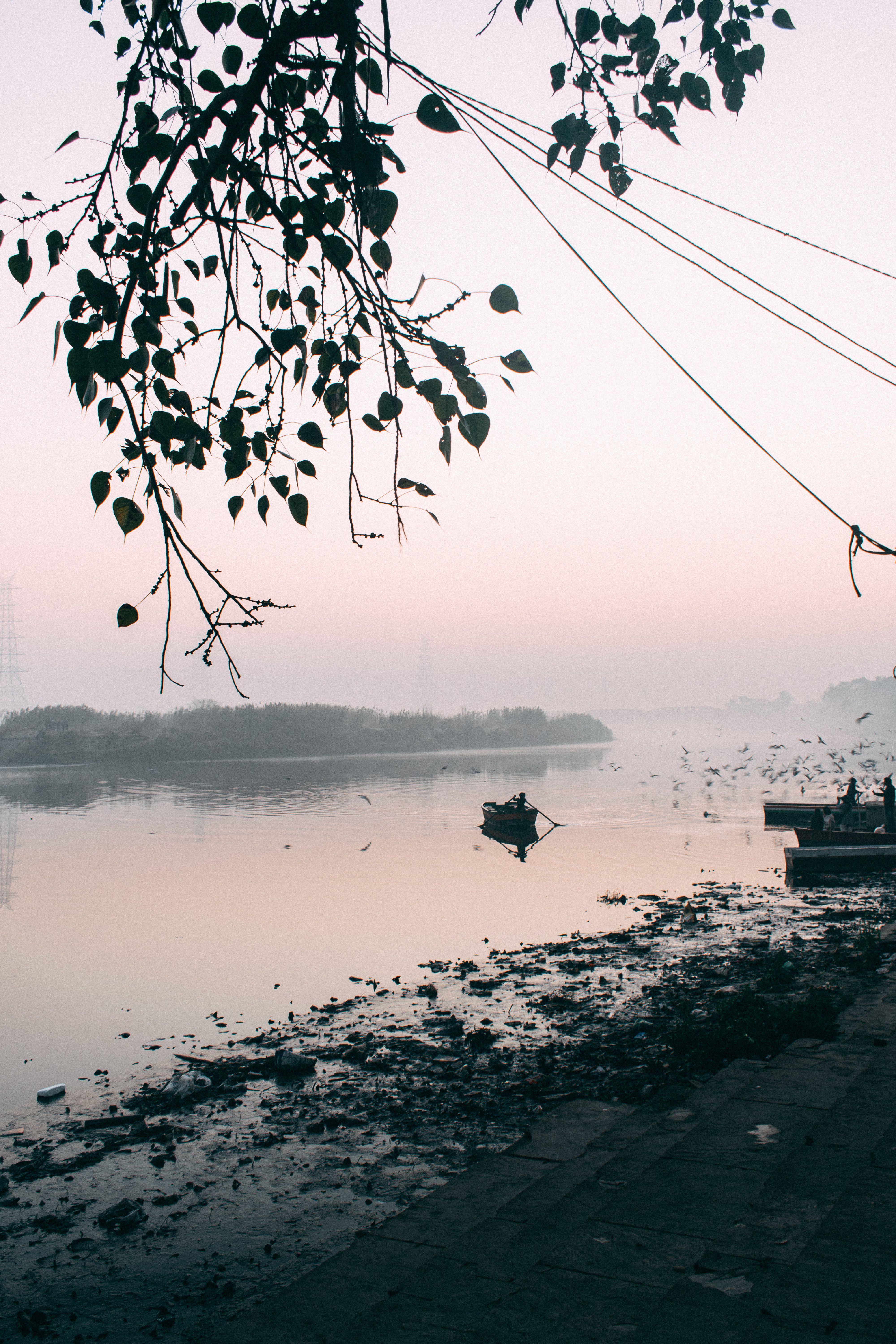 A tranquil boat on Yamuna River in New Delhi, silhouetted at dusk with serene reflection.