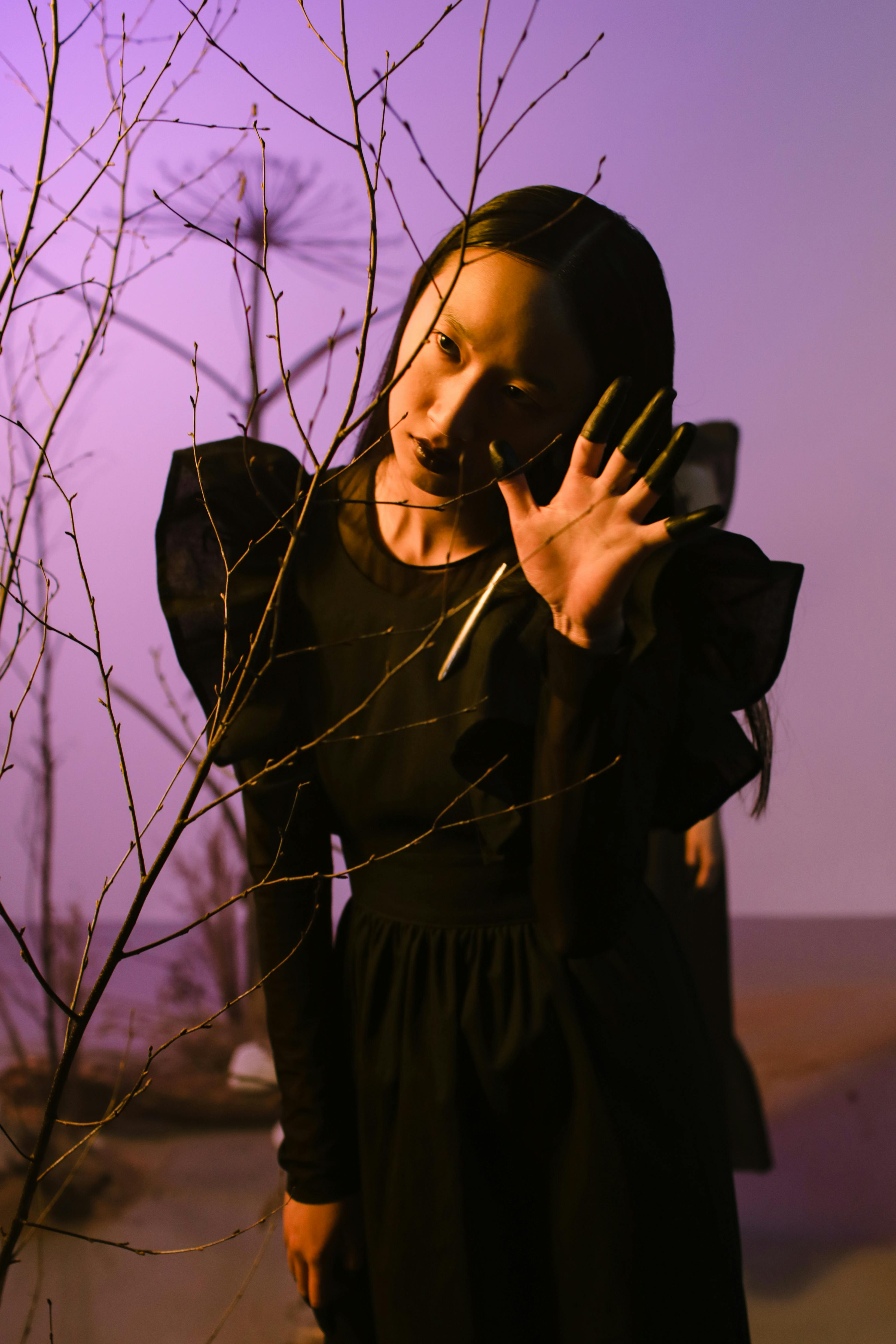 Dark conceptual portrait of a woman in black dress with ethereal vibe in studio setting.