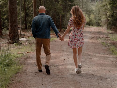 Free A romantic couple walks hand in hand along a serene forest path, enjoying nature. Stock Photo
