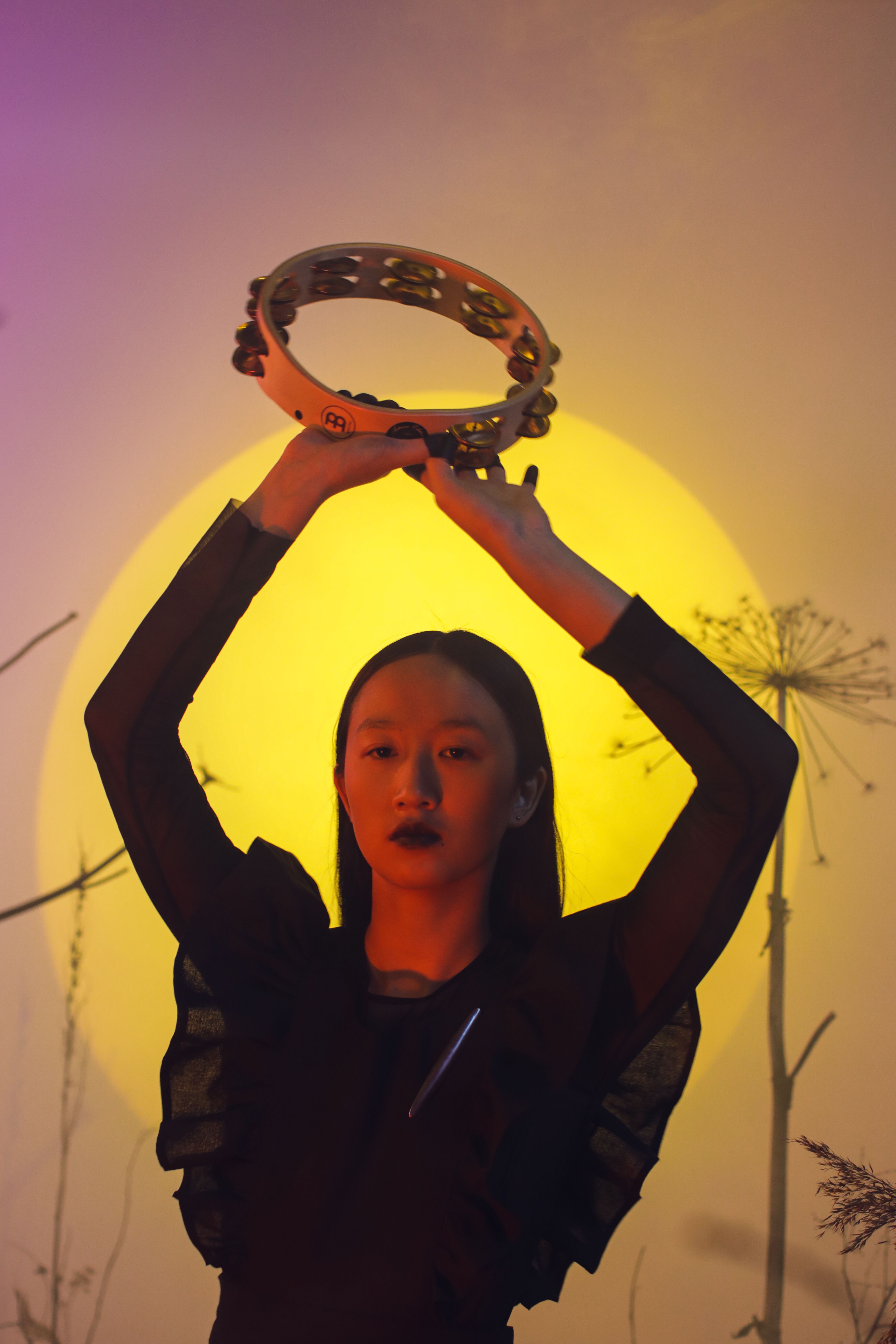 Conceptual photo of a woman with a tambourine in front of a glowing artistic background.