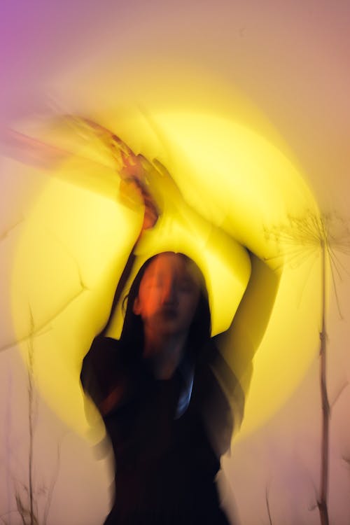 Blurry Studio Shot of a Woman Standing with Raised Arms 