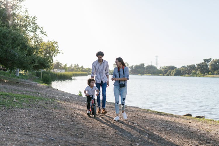 Parents Walking With Toddler Riding A Bicycle