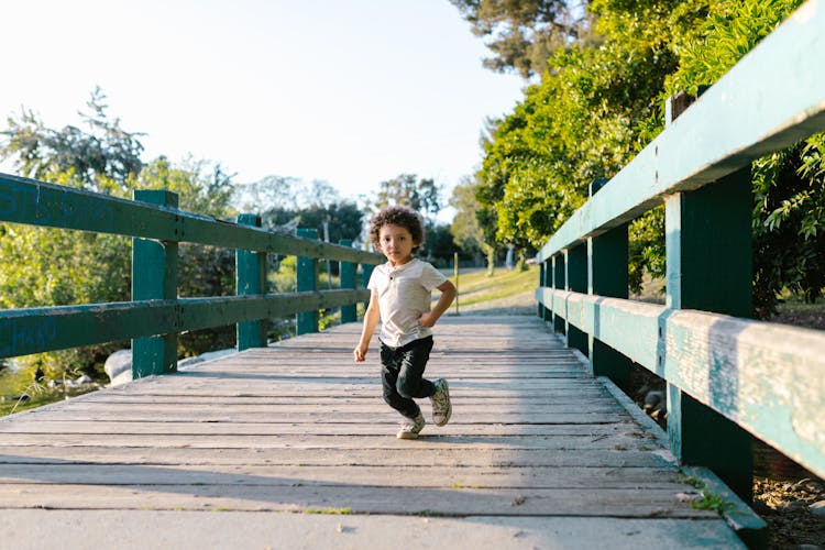 A Toddler Running On Wooden Bridge