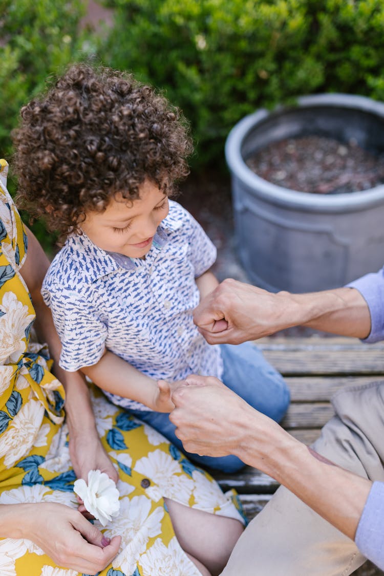 Little Boy Sitting Outside With His Parents 