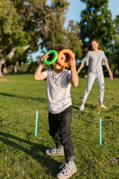 Free A cheerful child playing a fun game with colorful rings in a sunny park. Stock Photo
