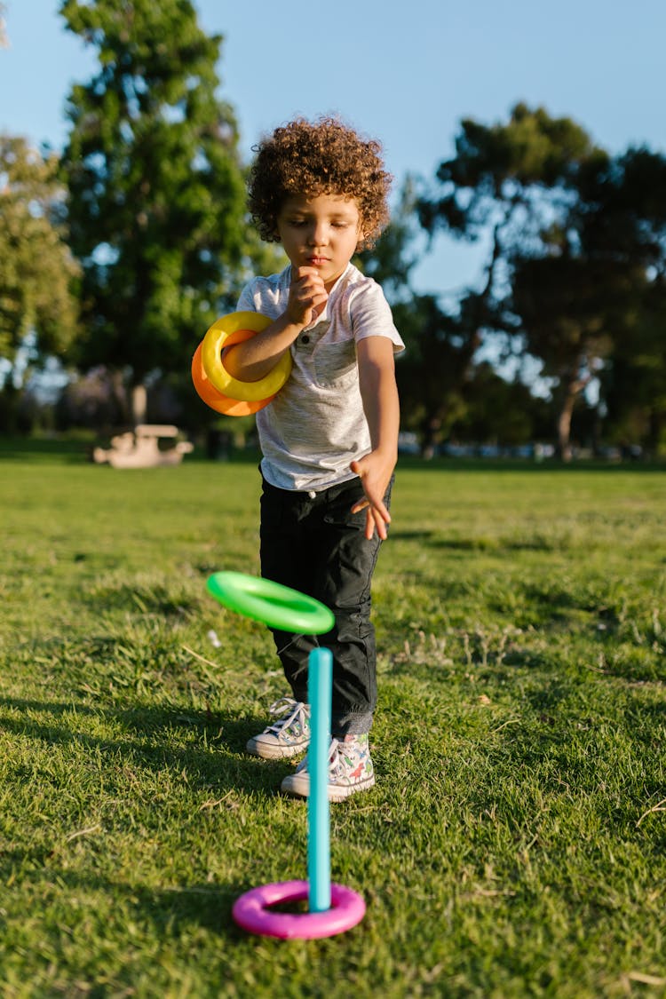 A Boy Playing Ring Toss In A Park 