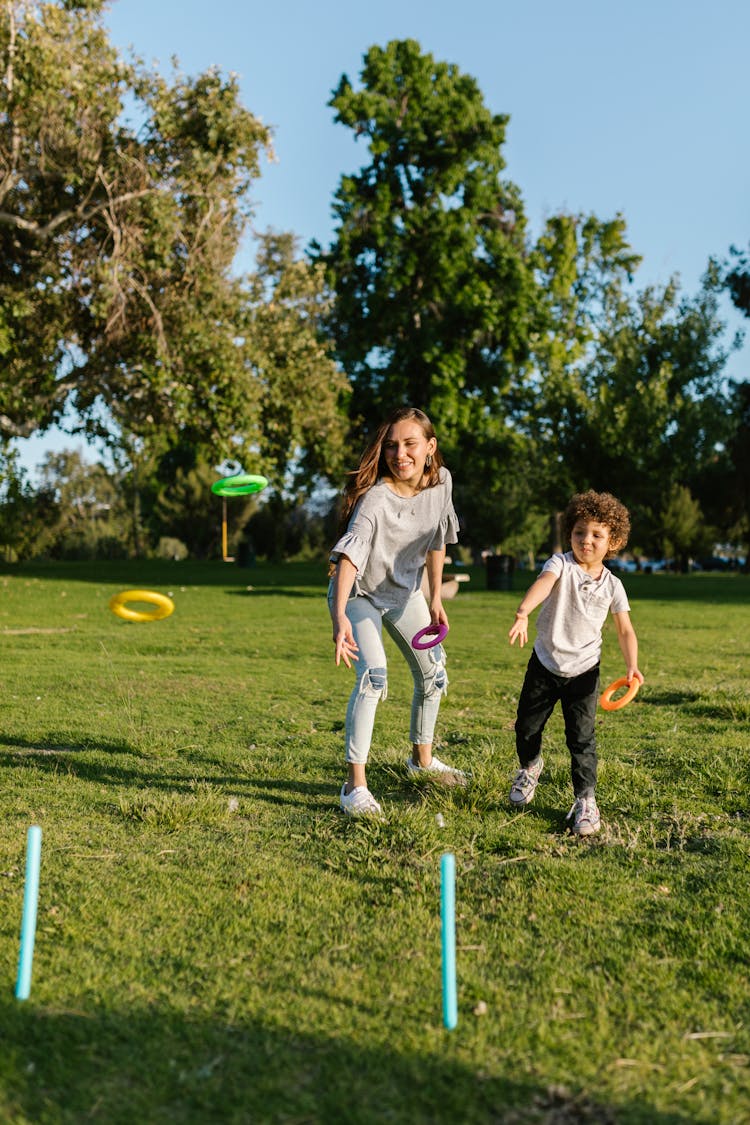 A Woman And A Young Boy Playing In The Park