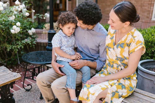 Family with a Little Boy Sitting on a Bench Together 