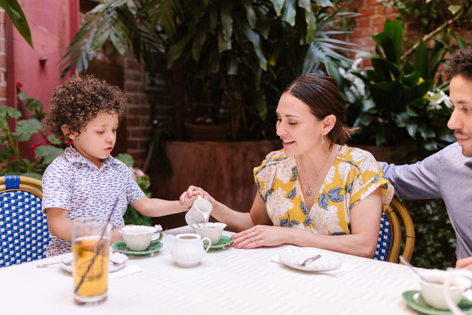 A family enjoying a cheerful tea time together in an inviting outdoor patio setting.