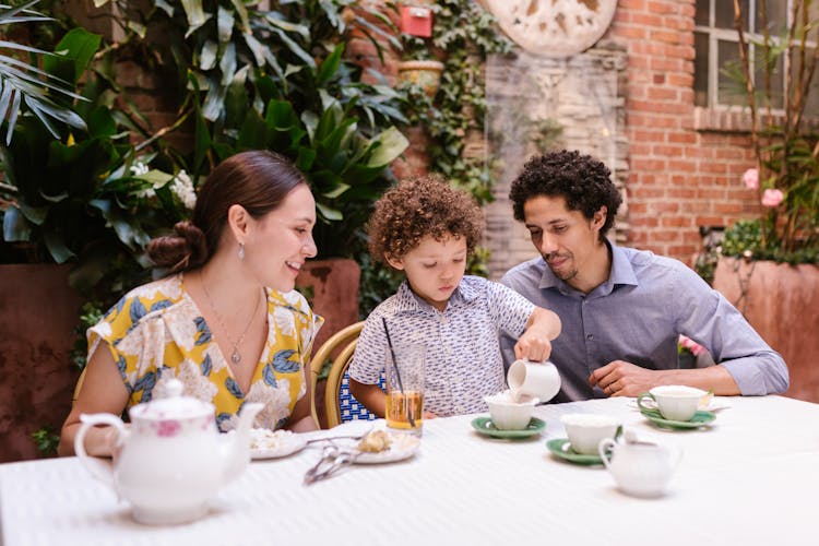 Parents With A Little Son Sitting At The Table In A Restaurant 