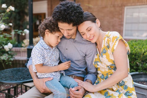 Family with a Little Son Sitting Outside and Hugging 