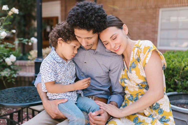 Family With A Little Son Sitting Outside And Hugging 